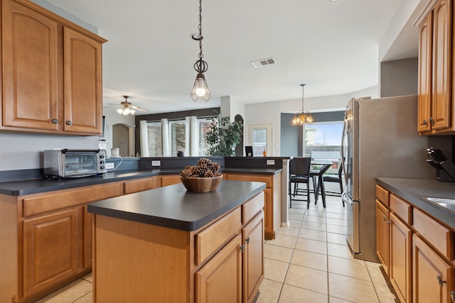 kitchen with pendant lighting, light tile patterned flooring, ceiling fan with notable chandelier, a kitchen island, and kitchen peninsula