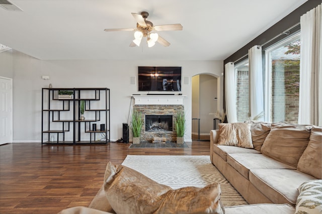 living room featuring a fireplace, ceiling fan, and dark wood-type flooring