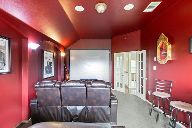 carpeted home theater room featuring french doors and lofted ceiling