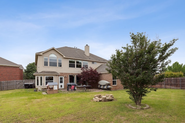 rear view of house with a yard and an outdoor fire pit