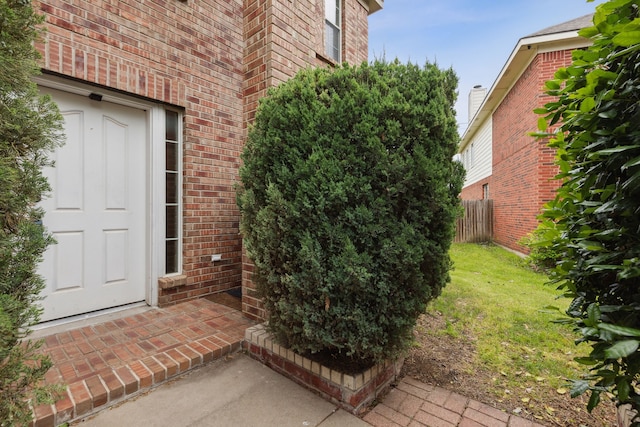 view of exterior entry featuring a lawn