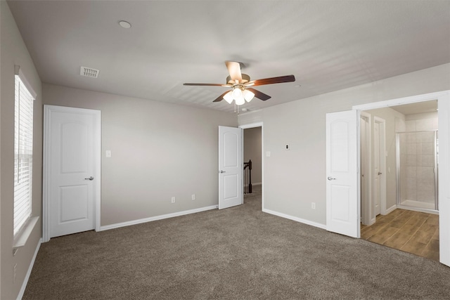 unfurnished bedroom featuring ceiling fan, ensuite bathroom, and dark carpet