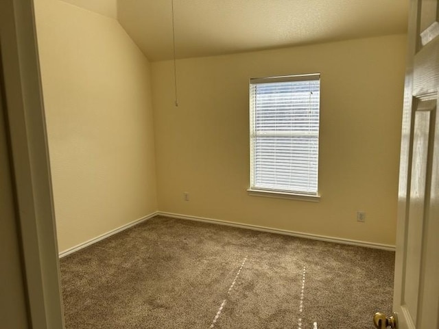 carpeted empty room with lofted ceiling