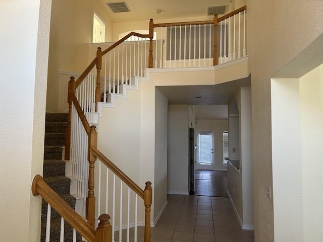 staircase with a towering ceiling and tile patterned floors