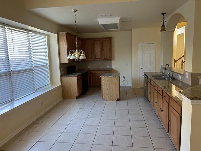 kitchen featuring backsplash, sink, light tile patterned floors, and pendant lighting