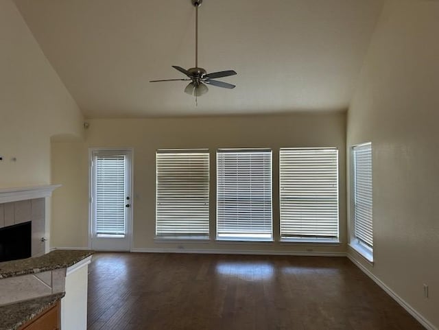 unfurnished living room featuring a tile fireplace, ceiling fan, plenty of natural light, and vaulted ceiling