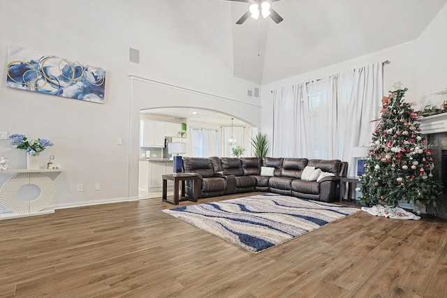 living room featuring ceiling fan, a high ceiling, and wood-type flooring