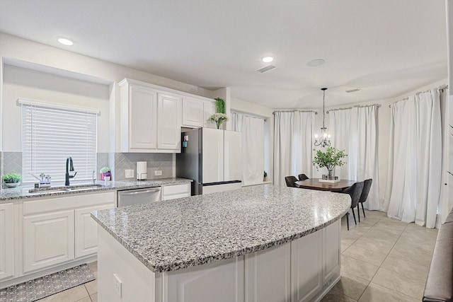 kitchen with a center island, stainless steel dishwasher, fridge, sink, and white cabinets