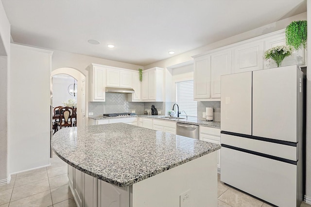 kitchen with a kitchen island, white cabinets, and light stone counters