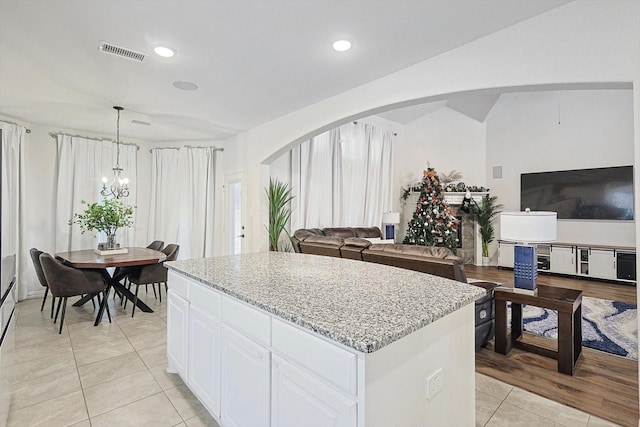 kitchen featuring light tile patterned floors, a chandelier, pendant lighting, white cabinets, and a center island