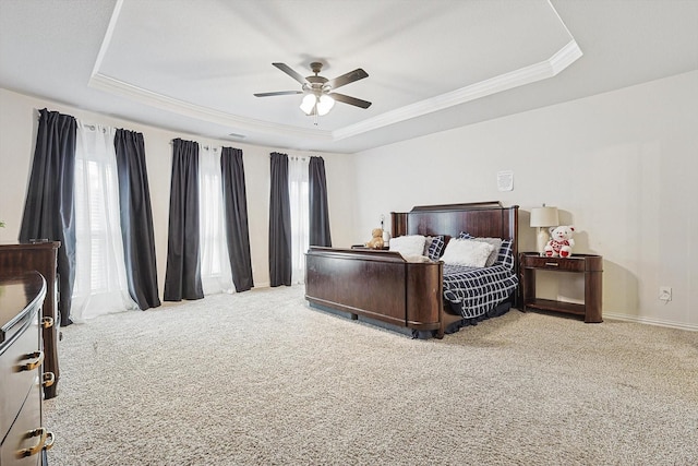 bedroom with ceiling fan, crown molding, light colored carpet, and a tray ceiling