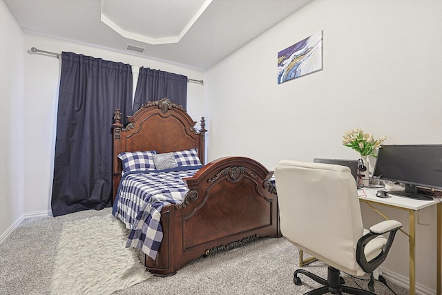 bedroom featuring light colored carpet and a raised ceiling