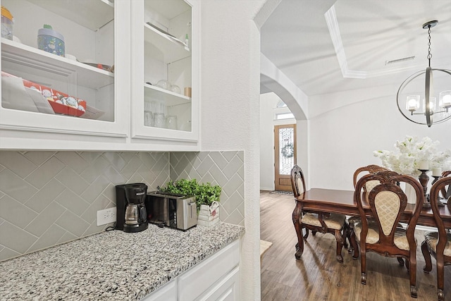 interior space with decorative light fixtures, decorative backsplash, white cabinetry, hardwood / wood-style flooring, and a chandelier