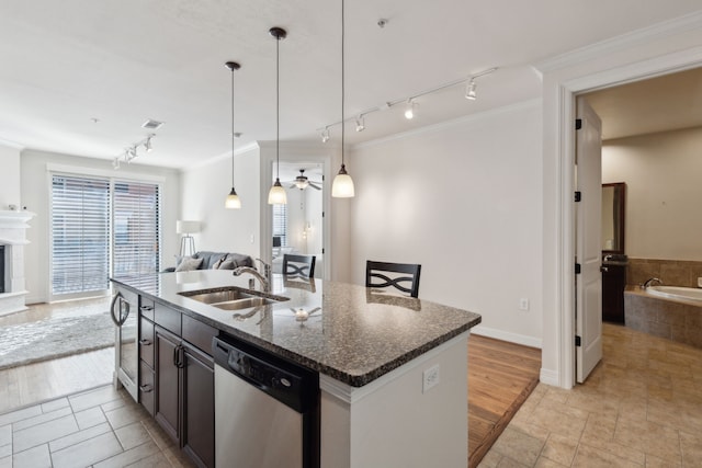 kitchen featuring a kitchen island with sink, sink, stainless steel dishwasher, dark stone counters, and crown molding