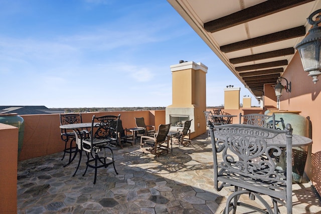 view of patio / terrace featuring exterior fireplace and outdoor dining area