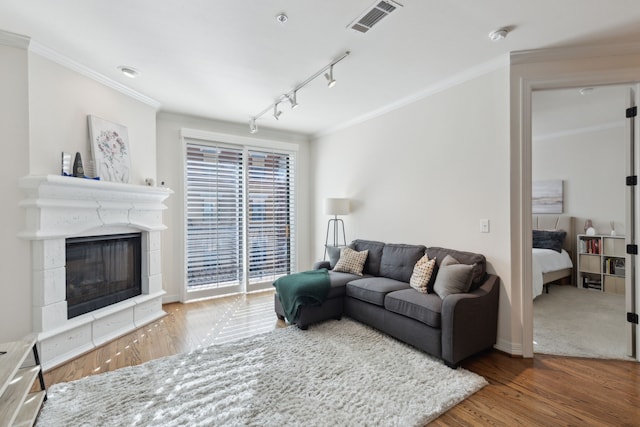 living room featuring visible vents, crown molding, a glass covered fireplace, and wood finished floors