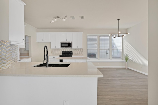 kitchen with white cabinets, decorative light fixtures, sink, kitchen peninsula, and a chandelier