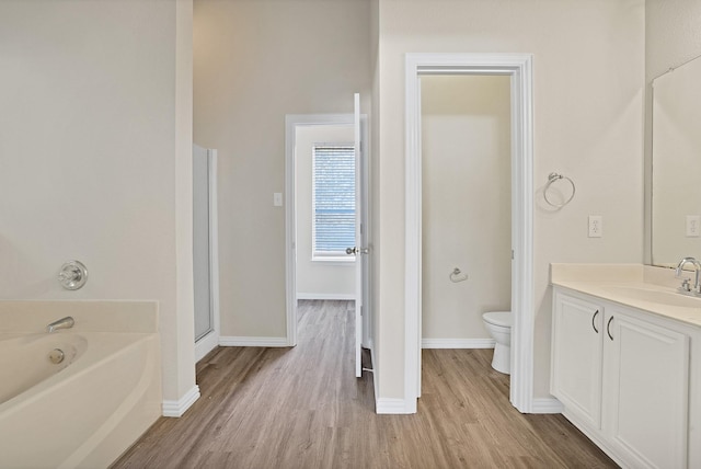 bathroom featuring hardwood / wood-style floors, toilet, a bath, and vanity