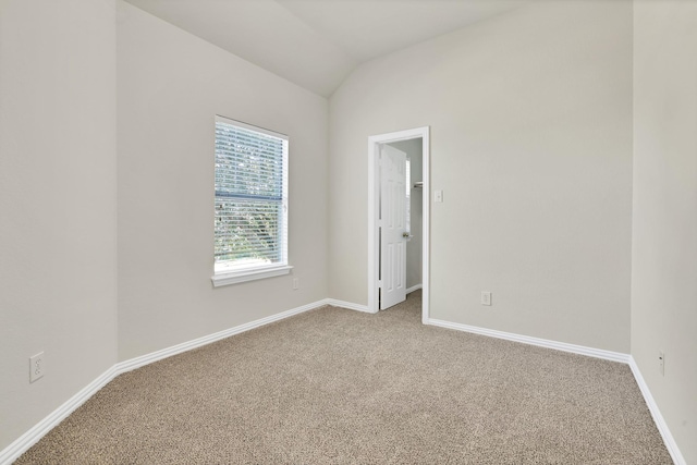 carpeted empty room with lofted ceiling