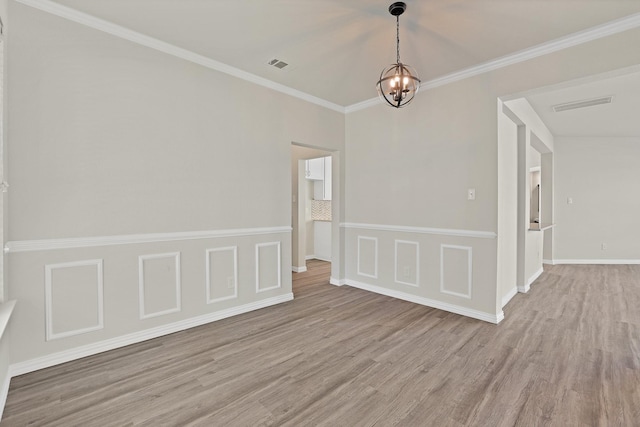 empty room featuring crown molding, a chandelier, and light hardwood / wood-style floors