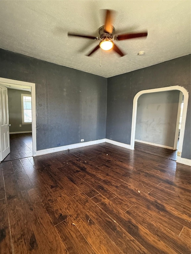 unfurnished room featuring ceiling fan, dark wood-type flooring, and a textured ceiling