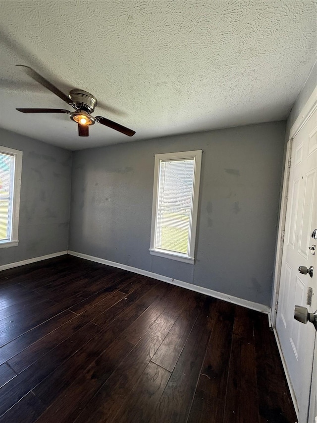 empty room featuring a textured ceiling, ceiling fan, and dark wood-type flooring