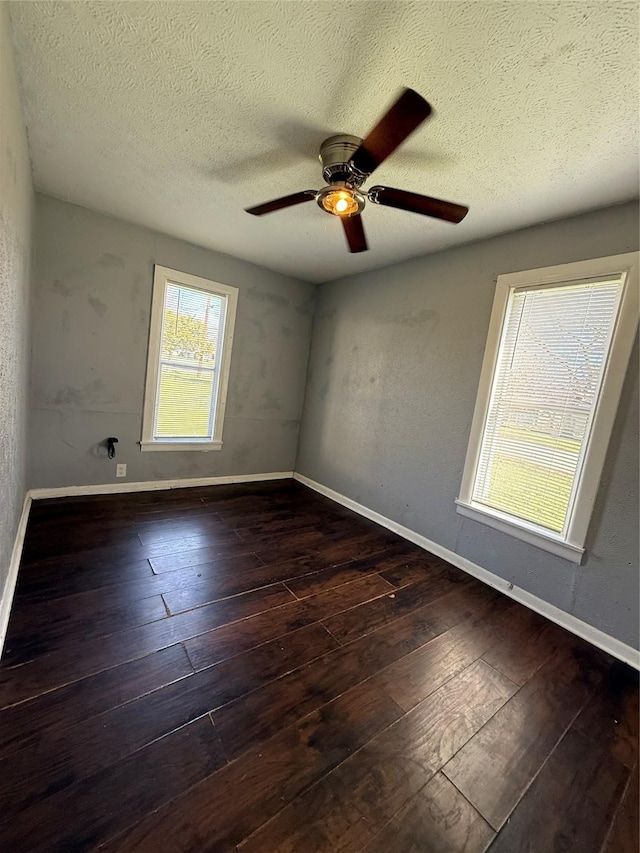 unfurnished room featuring a healthy amount of sunlight, dark wood-type flooring, and a textured ceiling