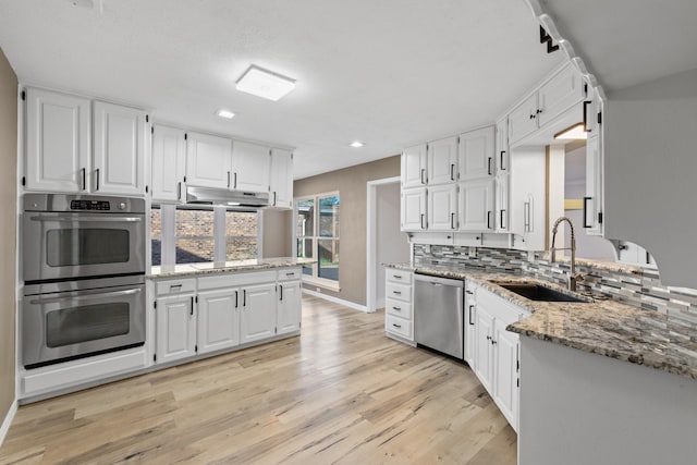 kitchen featuring decorative backsplash, appliances with stainless steel finishes, light stone countertops, sink, and white cabinets