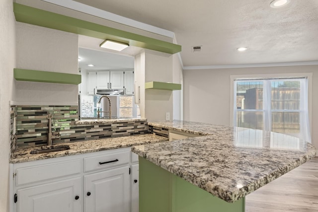 kitchen featuring kitchen peninsula, decorative backsplash, and white cabinetry