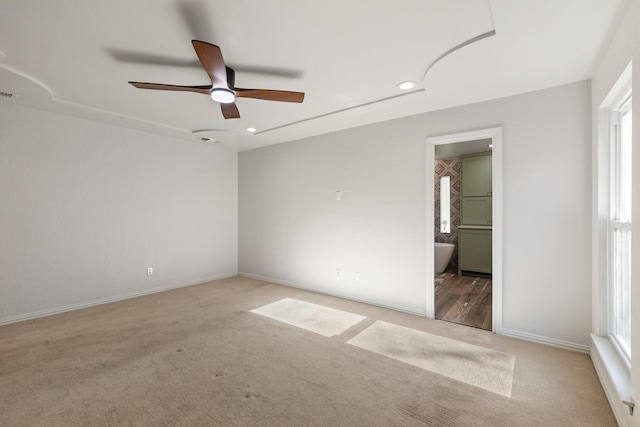 unfurnished bedroom with ceiling fan, ensuite bathroom, and light carpet