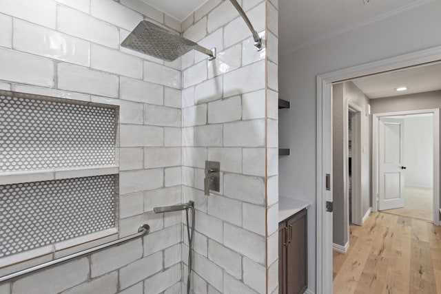 bathroom with tiled shower, hardwood / wood-style floors, vanity, and ornamental molding