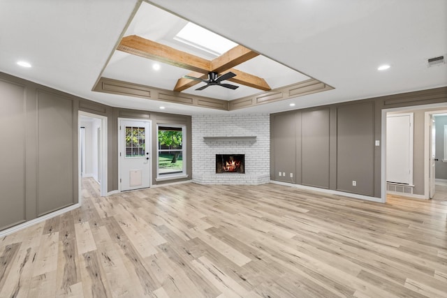 unfurnished living room featuring coffered ceiling, ceiling fan, light hardwood / wood-style flooring, and a brick fireplace