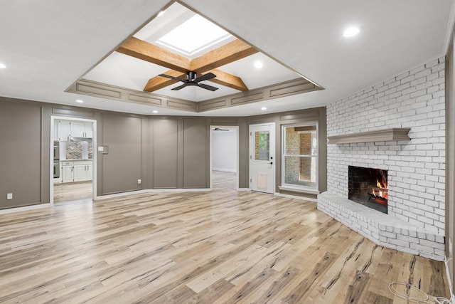 unfurnished living room with ceiling fan, light wood-type flooring, a fireplace, and coffered ceiling