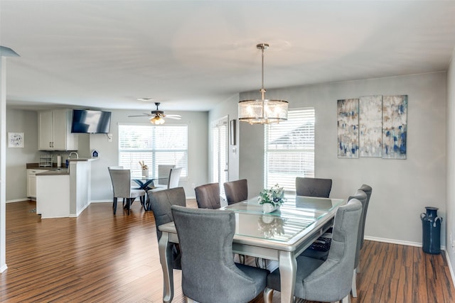 dining space featuring ceiling fan with notable chandelier, dark wood-style floors, and baseboards