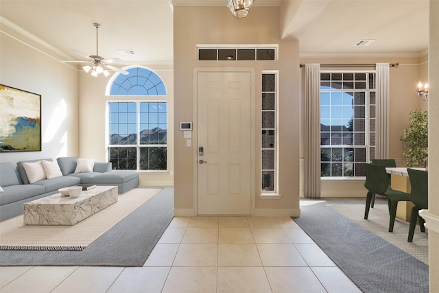 tiled entrance foyer with ceiling fan with notable chandelier and ornamental molding