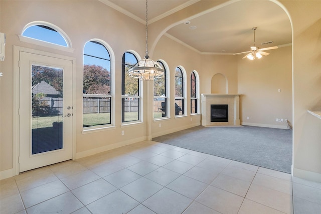 unfurnished living room with ceiling fan, ornamental molding, and light tile patterned flooring