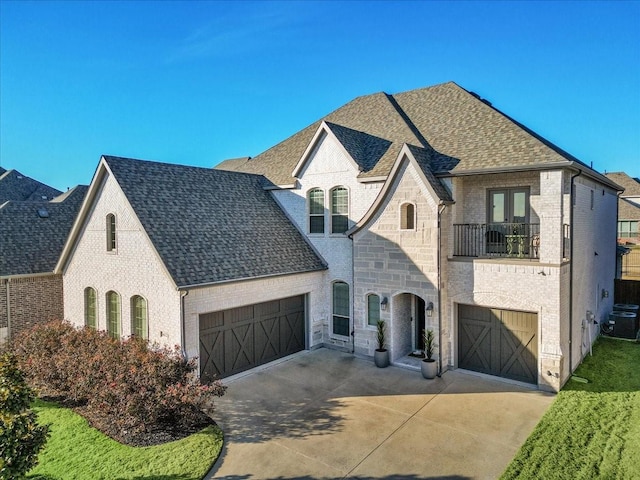 french country inspired facade featuring a balcony, a garage, and central AC unit