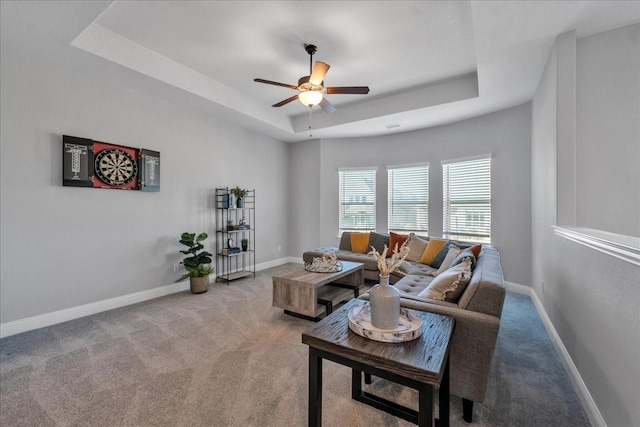 carpeted living room featuring ceiling fan and a raised ceiling