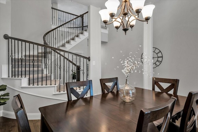 dining area featuring baseboards, wood finished floors, stairs, a high ceiling, and a chandelier