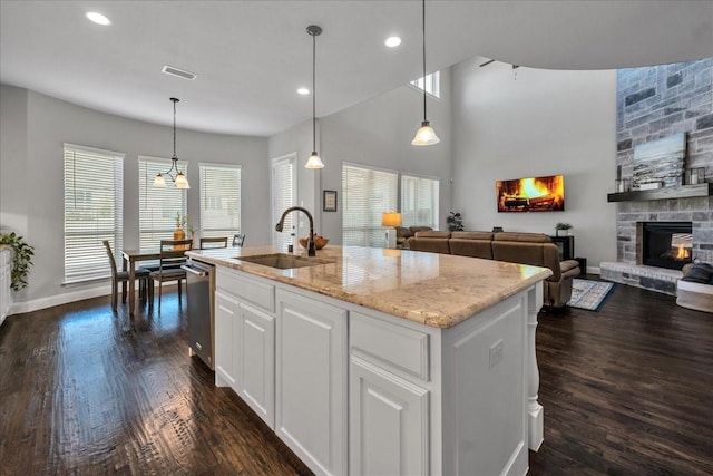 kitchen featuring white cabinetry, stainless steel dishwasher, a kitchen island with sink, and sink