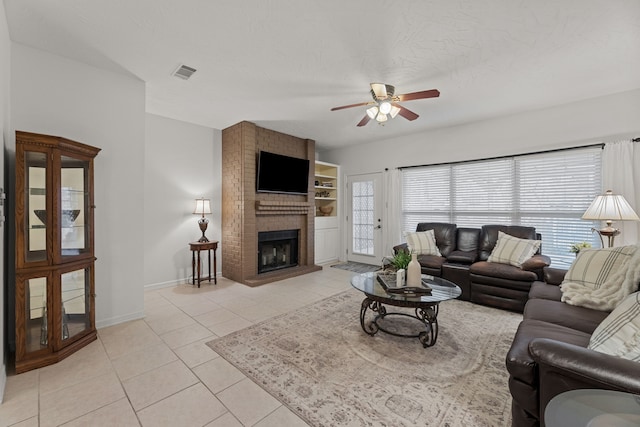 tiled living room featuring ceiling fan, a textured ceiling, and a brick fireplace