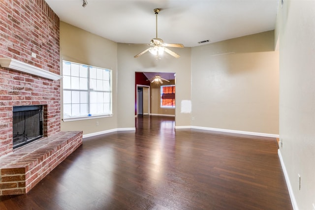 unfurnished living room featuring dark hardwood / wood-style flooring, a brick fireplace, and ceiling fan