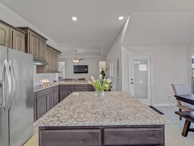 kitchen with ceiling fan, stainless steel fridge with ice dispenser, black electric stovetop, a kitchen island, and dark brown cabinets