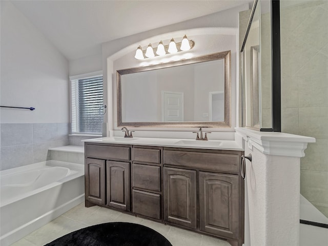 bathroom featuring tile patterned flooring, vanity, a washtub, and vaulted ceiling