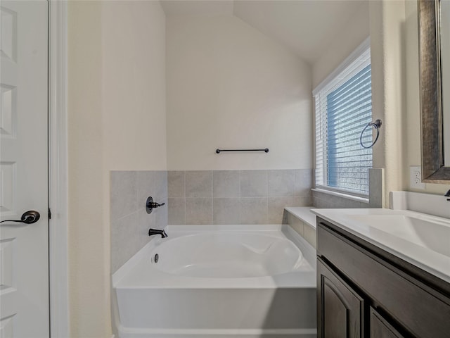 bathroom featuring vanity, lofted ceiling, and a washtub