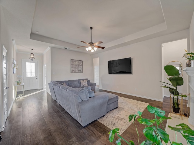 living room featuring dark hardwood / wood-style flooring, ceiling fan, and a raised ceiling