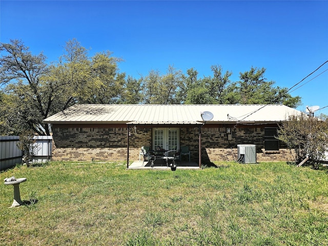 rear view of house featuring a lawn, french doors, cooling unit, and a patio