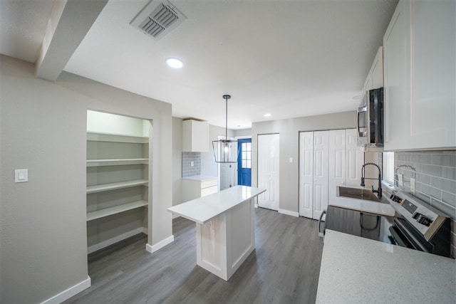 kitchen with pendant lighting, decorative backsplash, white cabinetry, and appliances with stainless steel finishes