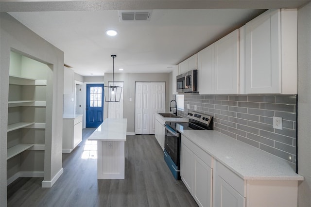 kitchen with white cabinetry, a center island, backsplash, pendant lighting, and appliances with stainless steel finishes