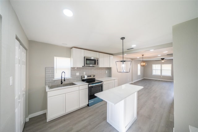 kitchen featuring appliances with stainless steel finishes, white cabinetry, ceiling fan, and sink